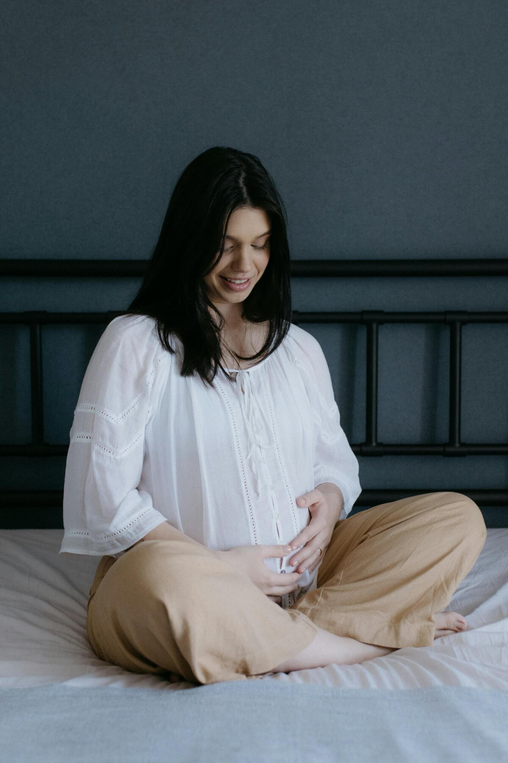 pregnant mother sitting on a bed