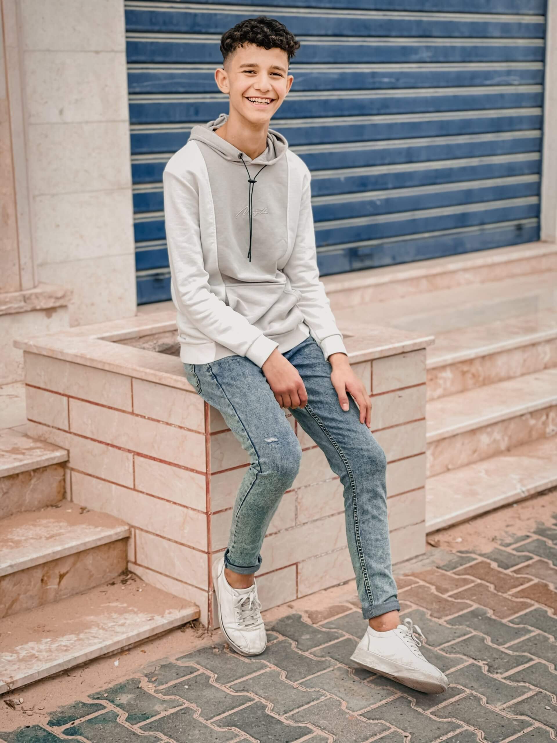 teen boy sitting against stairs